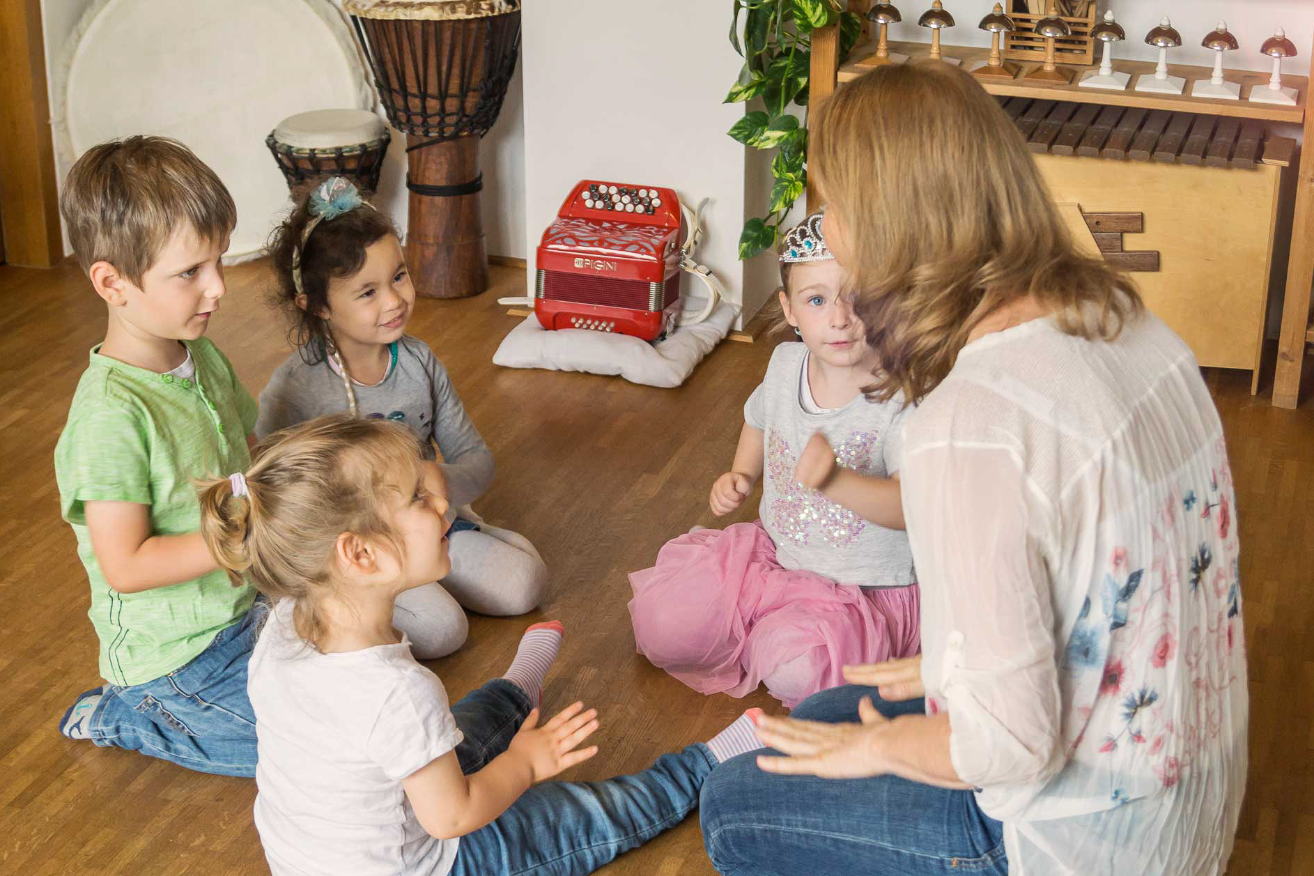 Heidi Savic mit vier Kindern in ihrer Musikschule am Boden sitzend.