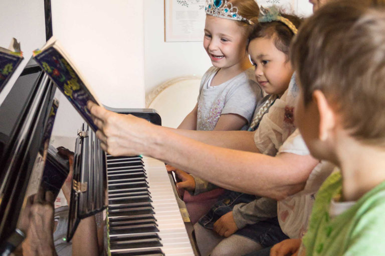 Heidrun Savic spielt gemeinsam mit Kindern auf einem Klavier in der Musikschule